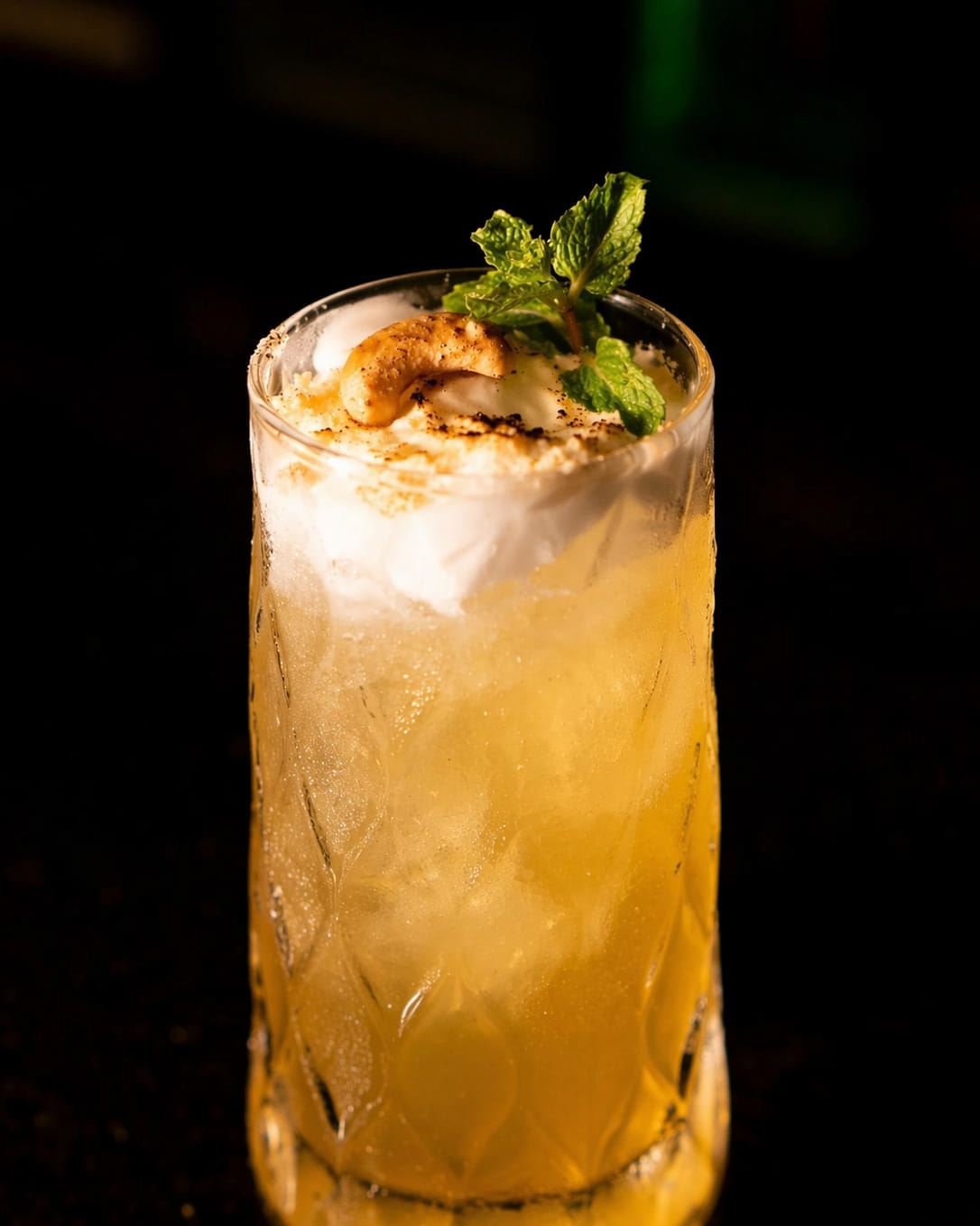 Drink autoral com espuma, castanha e hortelã servido em copo alto