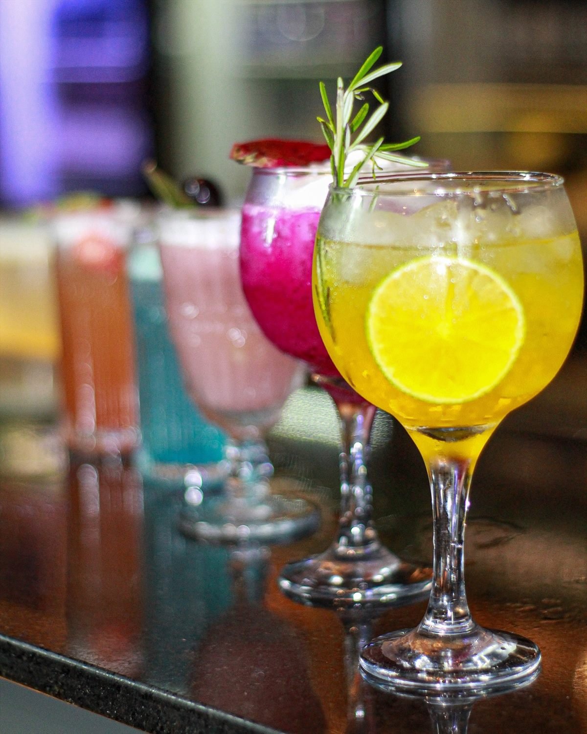 Drinks coloridos alinhados no balcão do BomBar