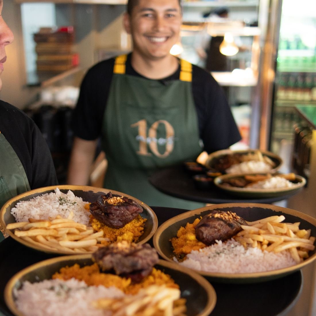 Equipe do BomBar levando bandejas com pratos do almoço para o salão